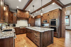 Kitchen with a center island, stainless steel appliances, tasteful backsplash, light wood-style floors, and light stone counters