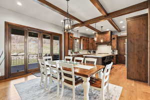 Dining space featuring beam ceiling, light wood-style floors, and a chandelier