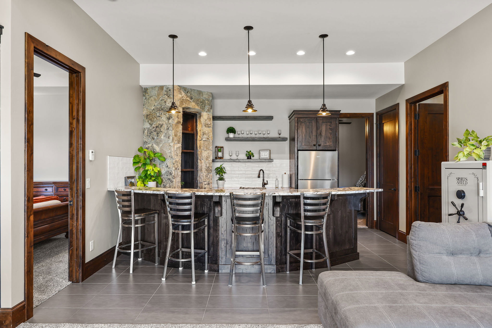 Kitchen with a peninsula, light stone countertops, a breakfast bar area, dark wood finish cabinetry, and dark tile patterned flooring