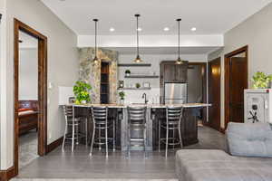 Kitchen with a peninsula, light stone countertops, a breakfast bar area, dark wood finish cabinetry, and dark tile patterned flooring