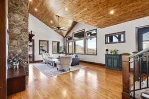 Living area featuring a vaulted wood ceiling, light wood-style floors, a ceiling fan, and a fireplace