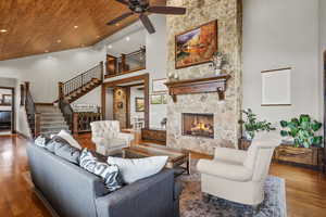 Living area featuring wood finished floors, a large fireplace, a ceiling fan, vaulted ceiling, and recessed lighting