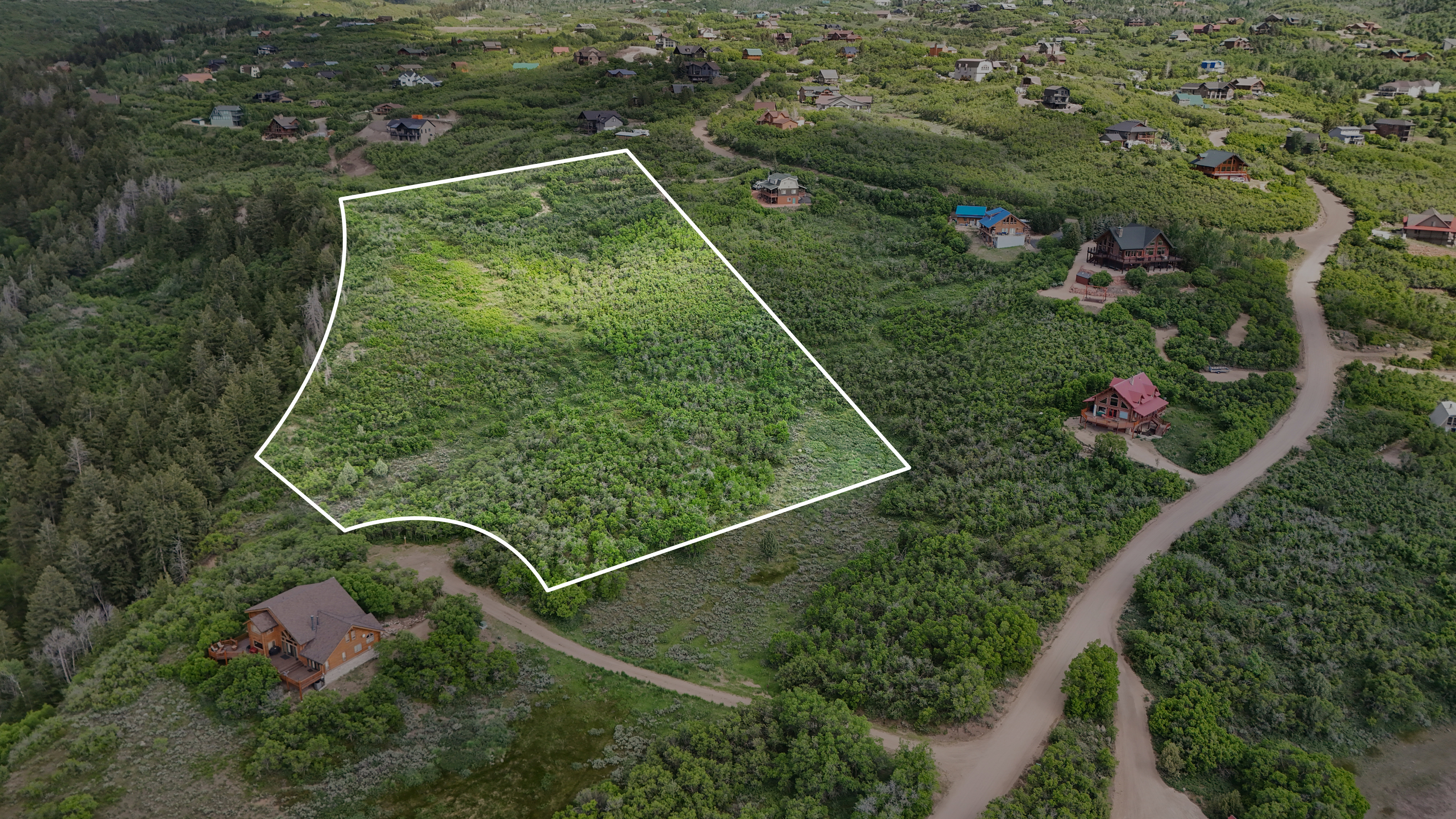 Aerial view of property's location featuring property parcel outlined and a forest