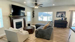 Living area featuring light wood-type flooring, recessed lighting, ceiling fan, and a glass covered fireplace