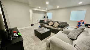Living area with recessed lighting, a textured ceiling, light colored carpet, and healthy amount of natural light