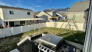 Fenced backyard featuring a patio area, a playground, and a mountain view