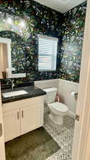 Bathroom with vanity, wallpapered walls, and a wainscoted wall