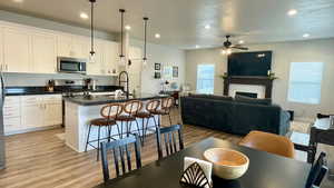 Kitchen featuring open floor plan, a kitchen breakfast bar, light wood finished floors, stainless steel appliances, and an island with sink