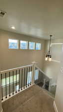 Stairs featuring a textured ceiling, carpet flooring, plenty of natural light, and a chandelier