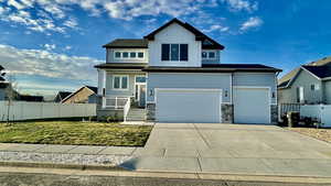 View of front of property featuring driveway, stone siding, a garage, and board and batten siding