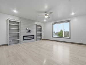 Unfurnished living room featuring ceiling fan, a fireplace, and light wood-style flooring