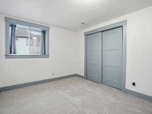 Unfurnished bedroom featuring light colored carpet, a closet, and a textured ceiling