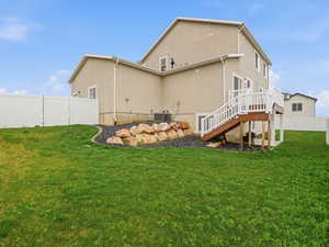 Rear view of property with a fenced backyard, stucco siding, and a wooden deck