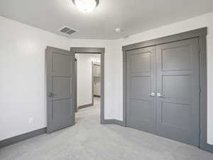 Unfurnished bedroom with light colored carpet and a closet