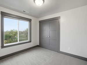 Unfurnished bedroom with light colored carpet and a closet
