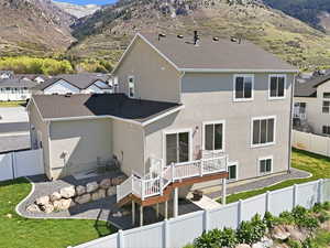 Rear view of house with a fenced backyard, stucco siding, a deck with mountain view, a patio area, and a residential view