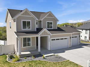 View of front facade with a shingled roof, covered porch, board and batten siding, a mountain view, and concrete driveway