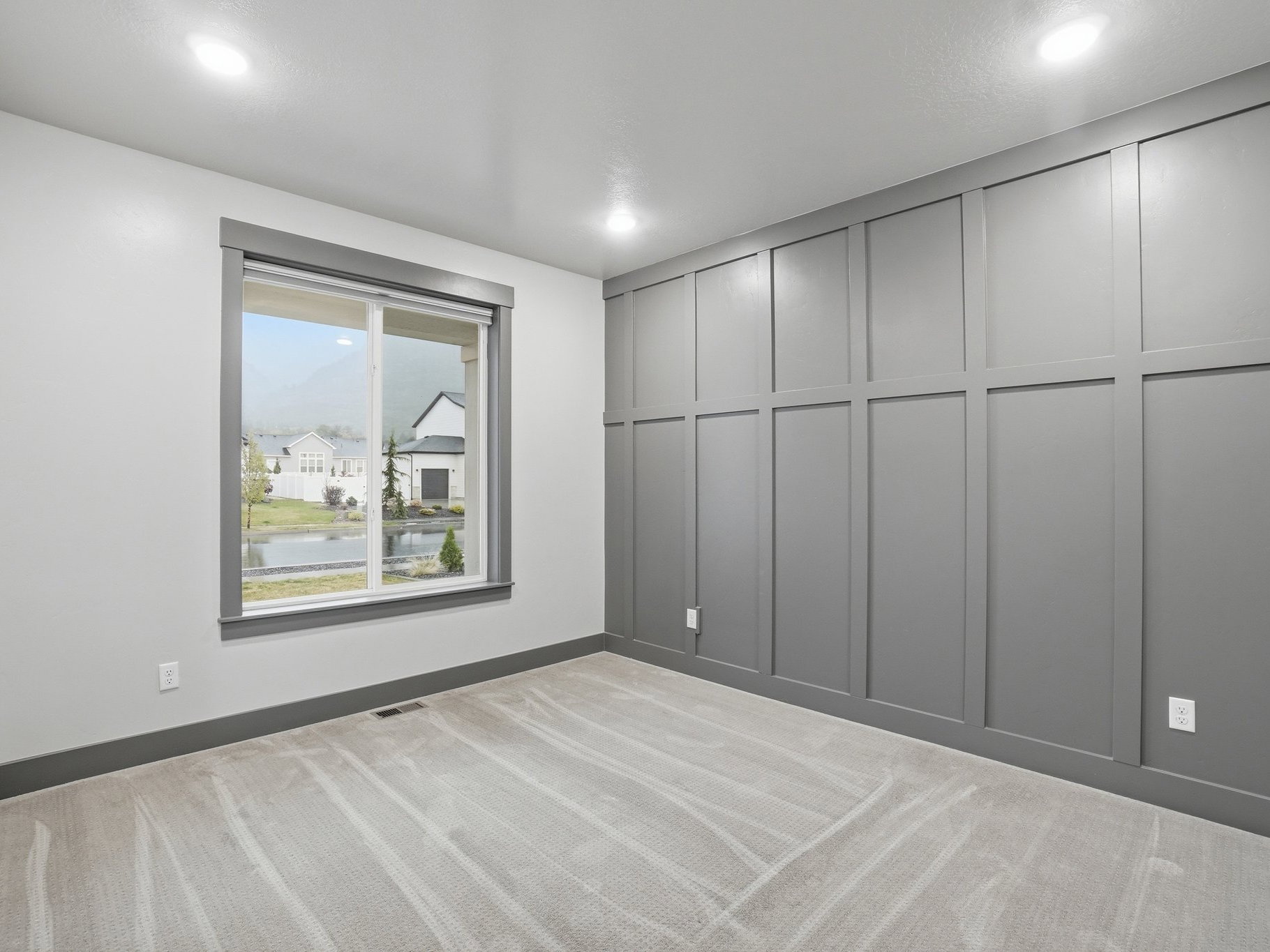 Unfurnished room with light colored carpet, a decorative wall, and a water view