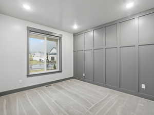 Unfurnished room with light colored carpet, a decorative wall, and a water view