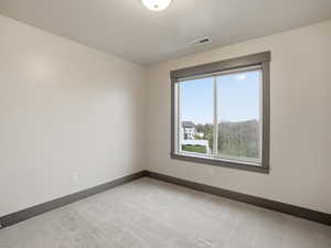Empty room with light colored carpet and baseboards