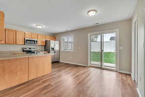 Kitchen featuring light countertops, stainless steel appliances, light wood finish cabinetry, and light wood-type flooring