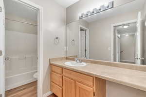 Full bathroom with vanity, light wood-type flooring, and shower / tub combination
