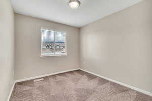 Carpeted spare room featuring baseboards