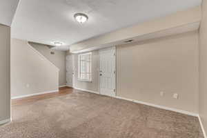 Basement with a textured ceiling and light colored carpet