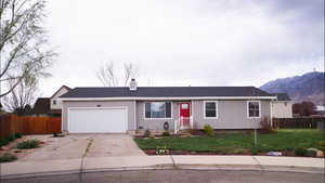Single story home with driveway, a garage, a chimney, roof with shingles, and a mountain view