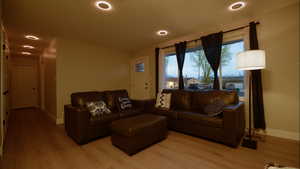 Living room with light wood finished floors and recessed lighting