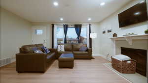 Living room featuring light wood-type flooring, a fireplace, and recessed lighting
