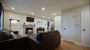 Living area featuring light wood-style flooring, a tiled fireplace, recessed lighting, and washer / dryer