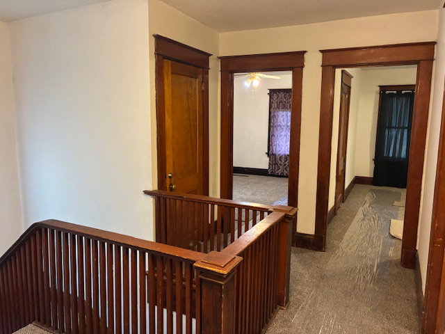 Hall featuring an upstairs landing and carpet flooring