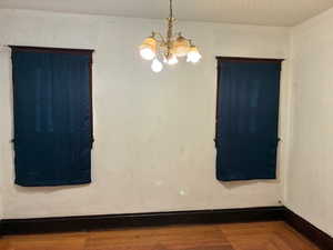 Spare room with wood finished floors and a chandelier