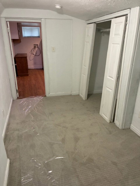 Unfurnished bedroom with a textured ceiling, carpet floors, and a closet