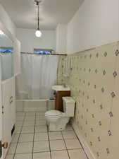 Bathroom featuring vanity, shower / bath combination with curtain, light tile patterned floors, and tile walls