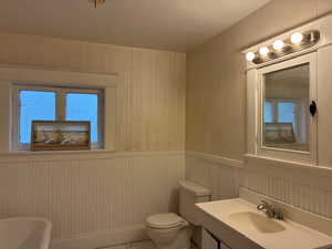 Bathroom with vanity, wood walls, healthy amount of natural light, light tile patterned floors, and wainscoting