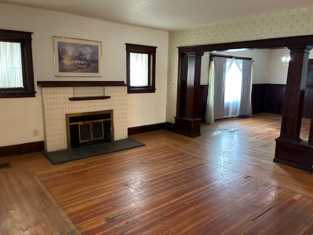 Unfurnished living room featuring hardwood / wood-style floors, ornate columns, and a fireplace