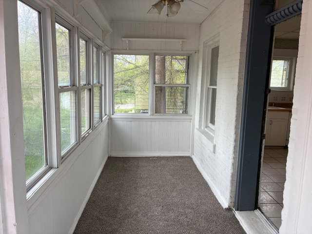 Unfurnished sunroom featuring a ceiling fan
