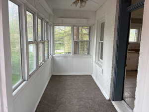 Unfurnished sunroom featuring a ceiling fan
