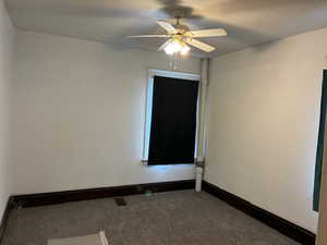 Empty room with dark carpet and ceiling fan