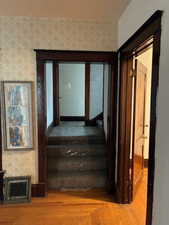 Stairs with wood finished floors and wallpapered walls