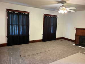Carpeted living room featuring a fireplace with flush hearth and ceiling fan
