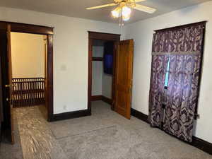 Unfurnished bedroom featuring light colored carpet, ceiling fan, and a walk in closet
