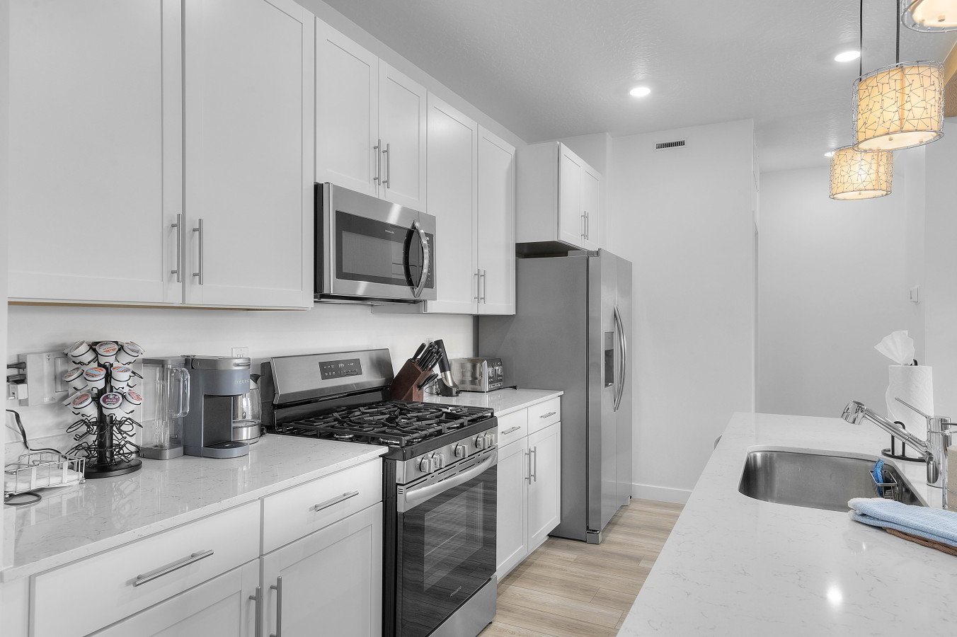 Kitchen with stainless steel appliances, white cabinetry accented by white quartz  countertops whit with a hint of gray.