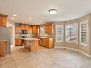 Kitchen with stainless steel appliances, wood finish cabinetry, light countertops, recessed lighting, and a kitchen island