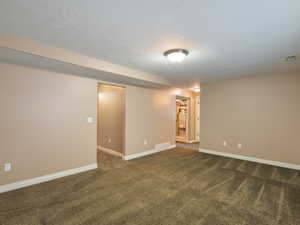 Unfurnished room with dark carpet and a textured ceiling