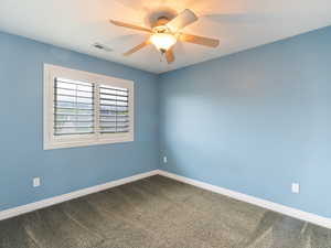 Unfurnished room with dark colored carpet and ceiling fan