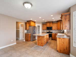 Kitchen featuring a center island, wood finish cabinetry, stainless steel appliances, recessed lighting, and light countertops