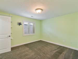 Spare room with dark carpet and a textured ceiling